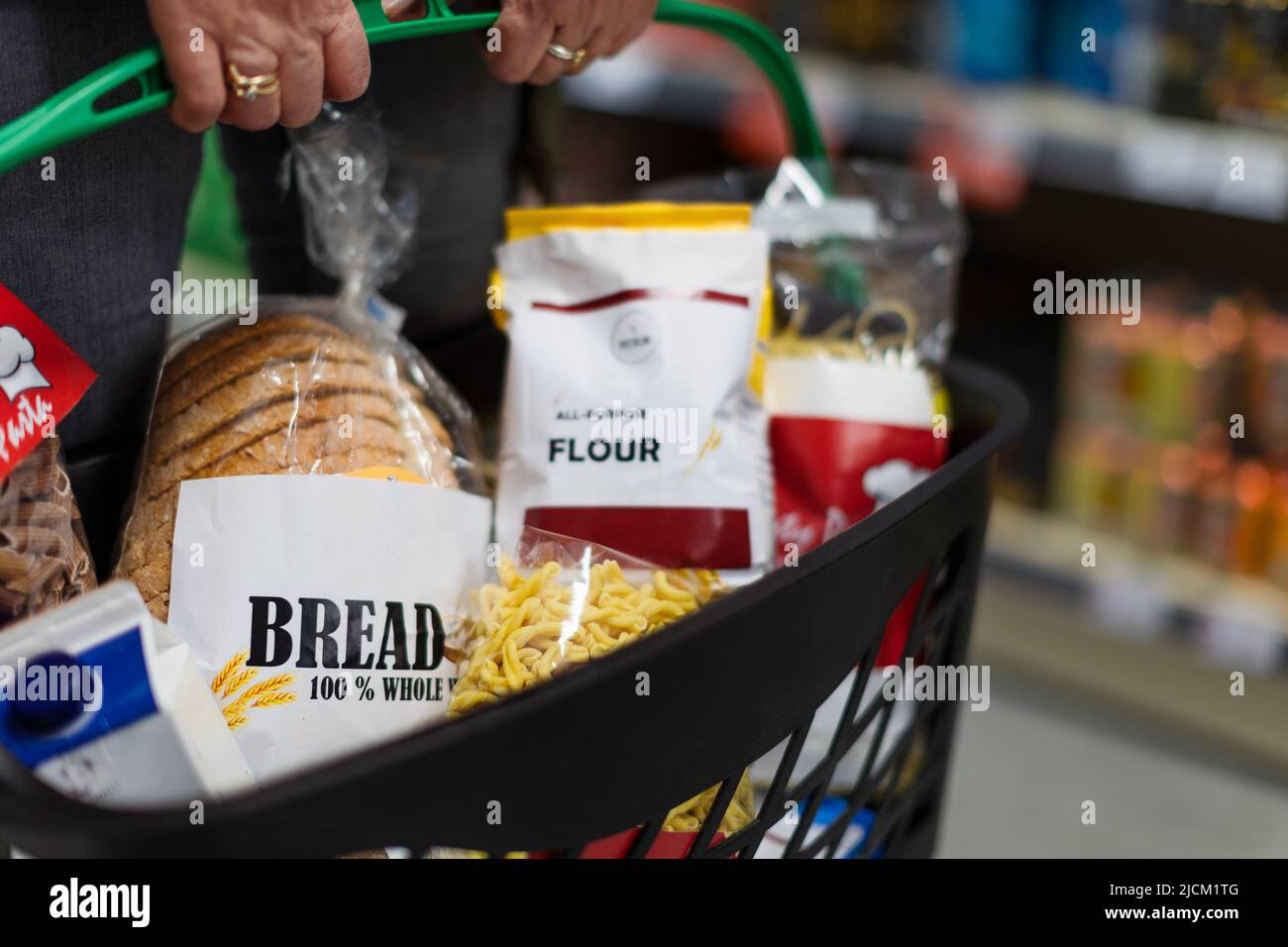 Donna che acquista al supermercato, lei sta trasportando il carrello pieno di shopping, primo piano. Foto Stock