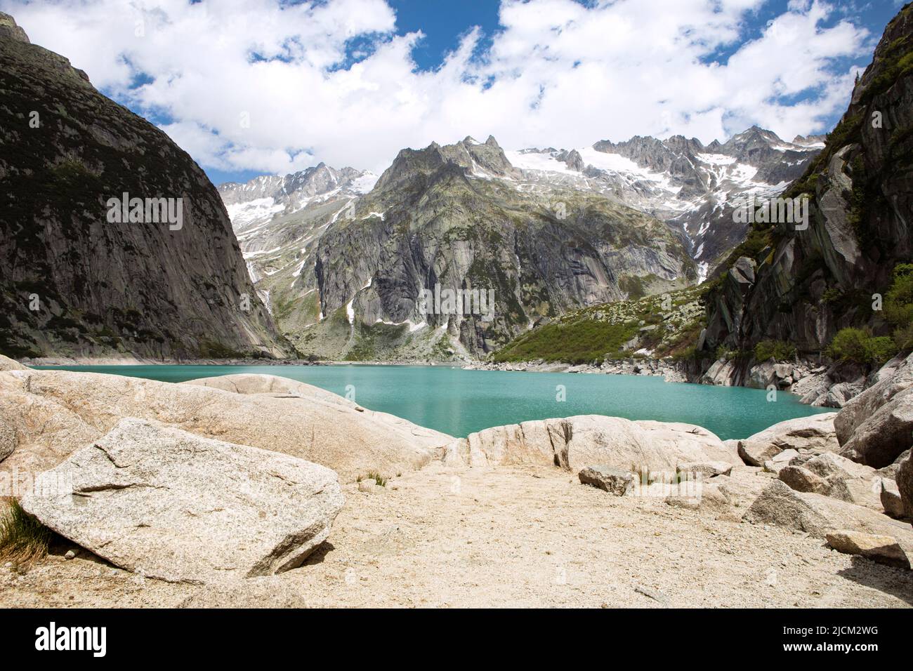 Alpi montagne bellissimo paesaggio con lago d'acqua turchese. Alte montagne parzialmente ombreggiate. Natura panoramica del lago di Gelmer lago di riserva, soleggiata giorno d'estate. Foto Stock