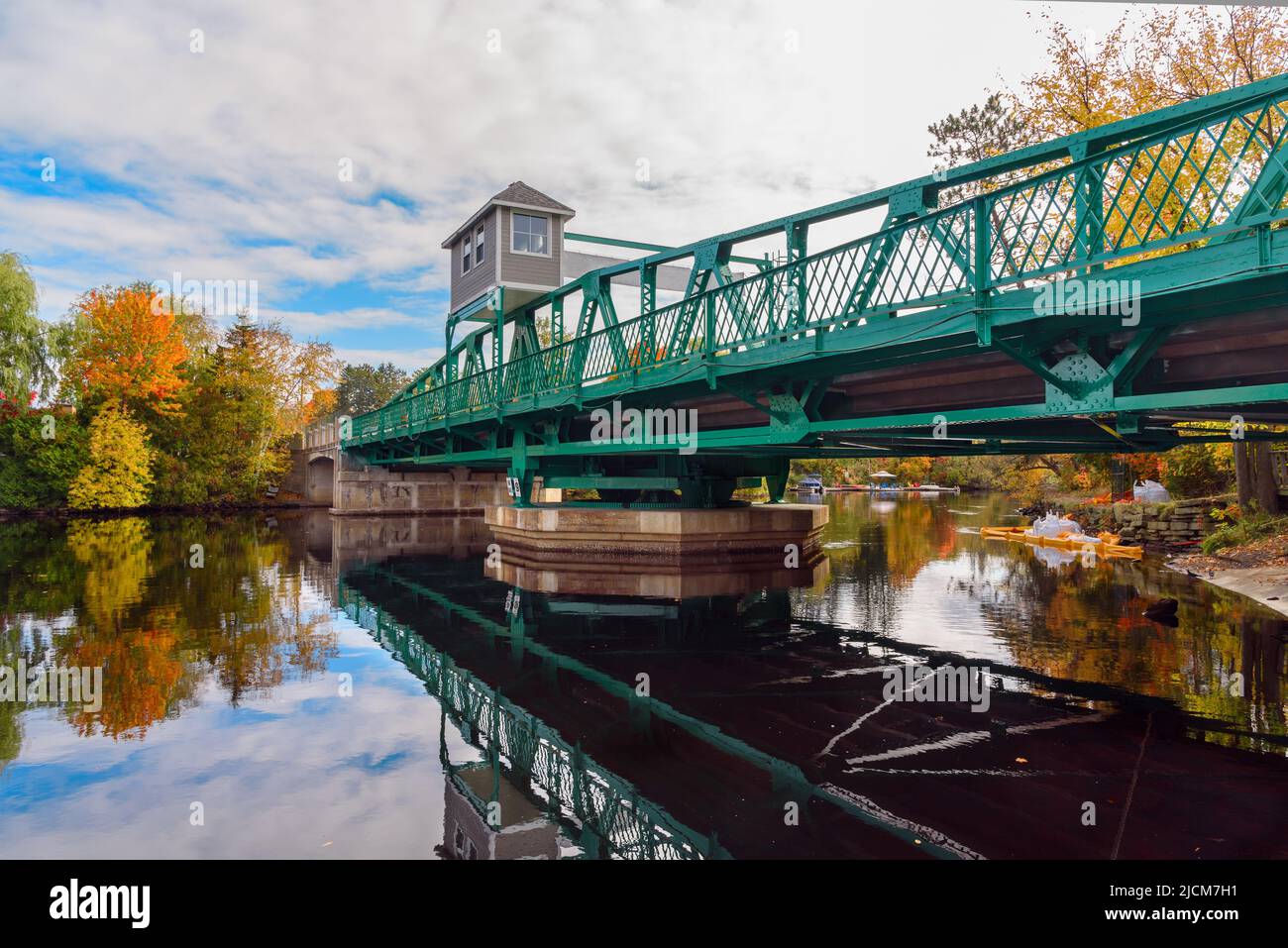 Altalena il ponte su un fiume in una giornata d'autunno poco nuvolosa. Riflessione in acqua. Foto Stock