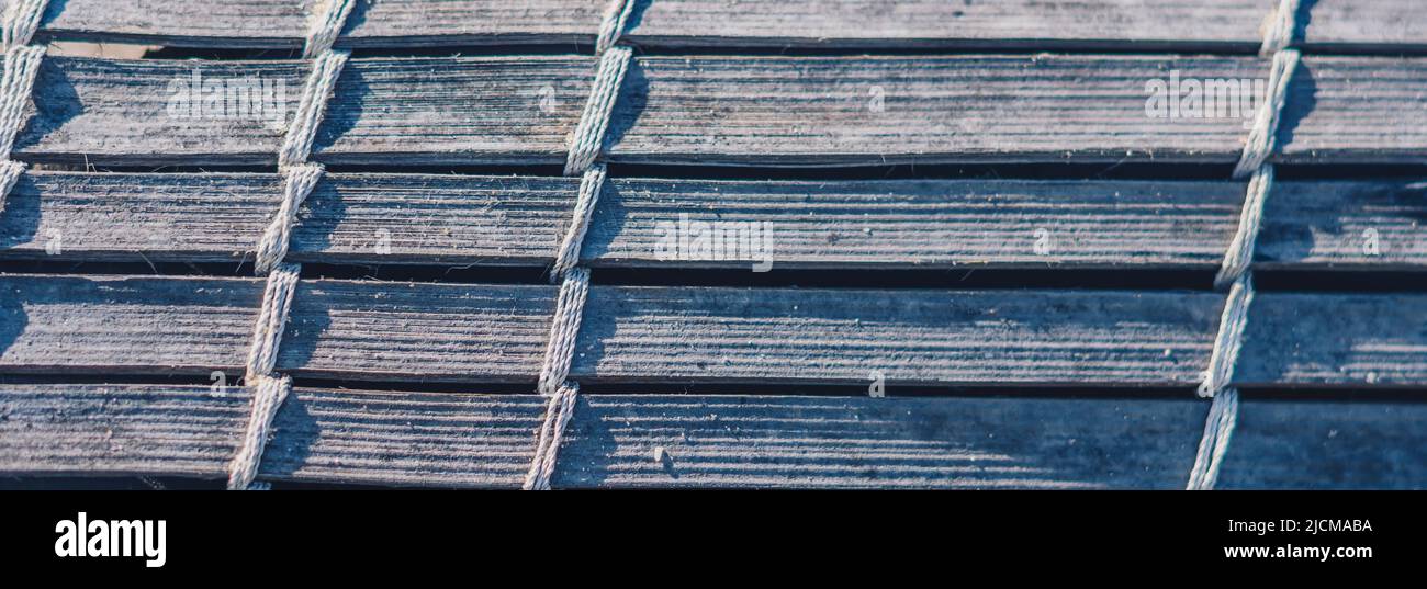 BANNER tappeto di bambù tessuto vecchio, ruvido tessuto sporco, frammento banner. Linee verticali orizzontali diagonali, ombra a contrasto. Spazio di copia per il testo. Astratto Foto Stock
