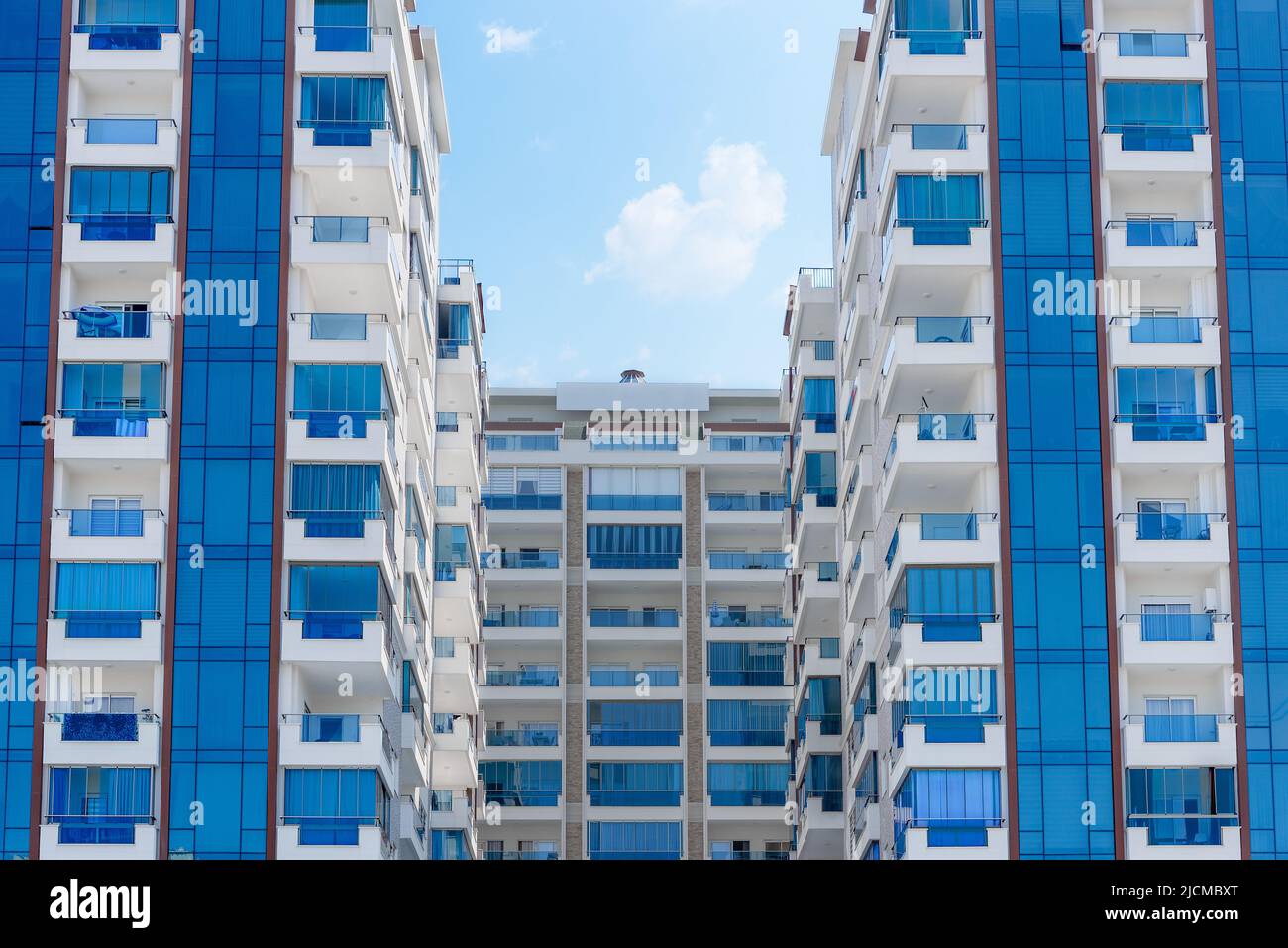 Vista astratta di un complesso residenziale multi-familiare di condomini con finestre balconi dipinti in blu e bianco. Architettura di sfondo. Foto Stock