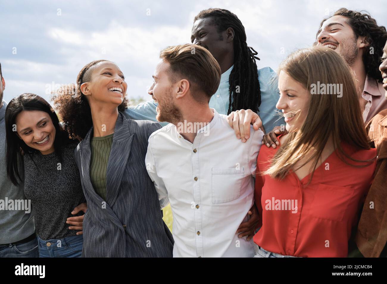 Gruppo multietnico di amici che si divertono insieme all'aperto - amici milleniali che ridono insieme all'esterno Foto Stock