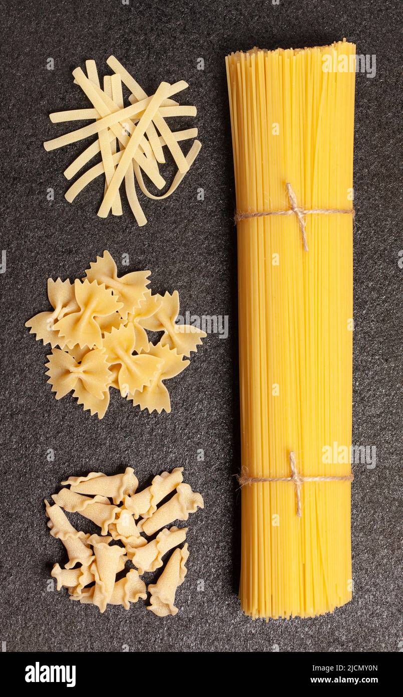Spaghetti con vari tipi e forme di pasta italiana su fondo nero. Vista dall'alto. Foto Stock