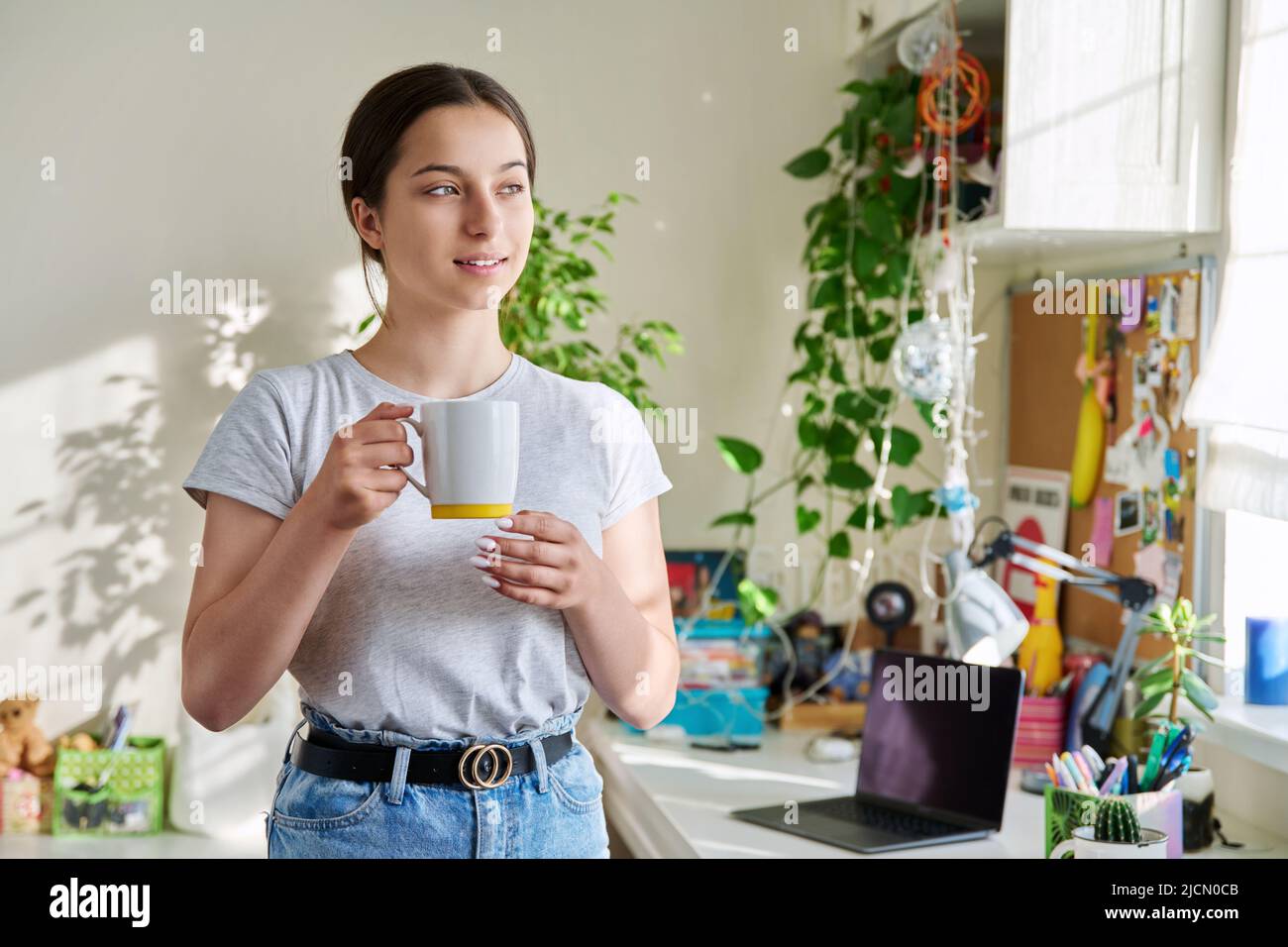 Ragazza adolescente 14, 15 anni che tiene la tazza, in piedi a casa Foto Stock