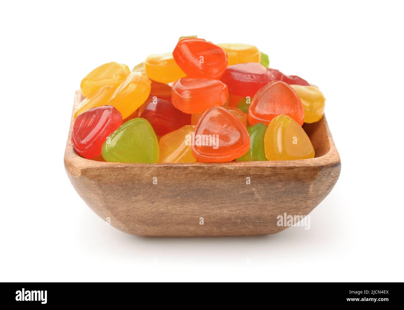 Vista frontale di colorate caramelle di frutta dura in ciotola di legno isolato su bianco Foto Stock