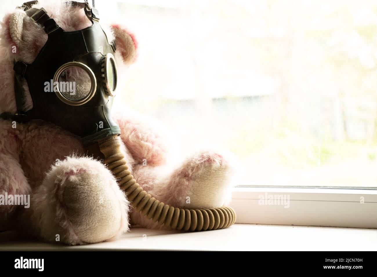 Orsacchiotto in una maschera a gas siede sulla finestra della casa, attacco a gas, guerra in Ucraina, attacco chimico durante la guerra in Ucraina Foto Stock