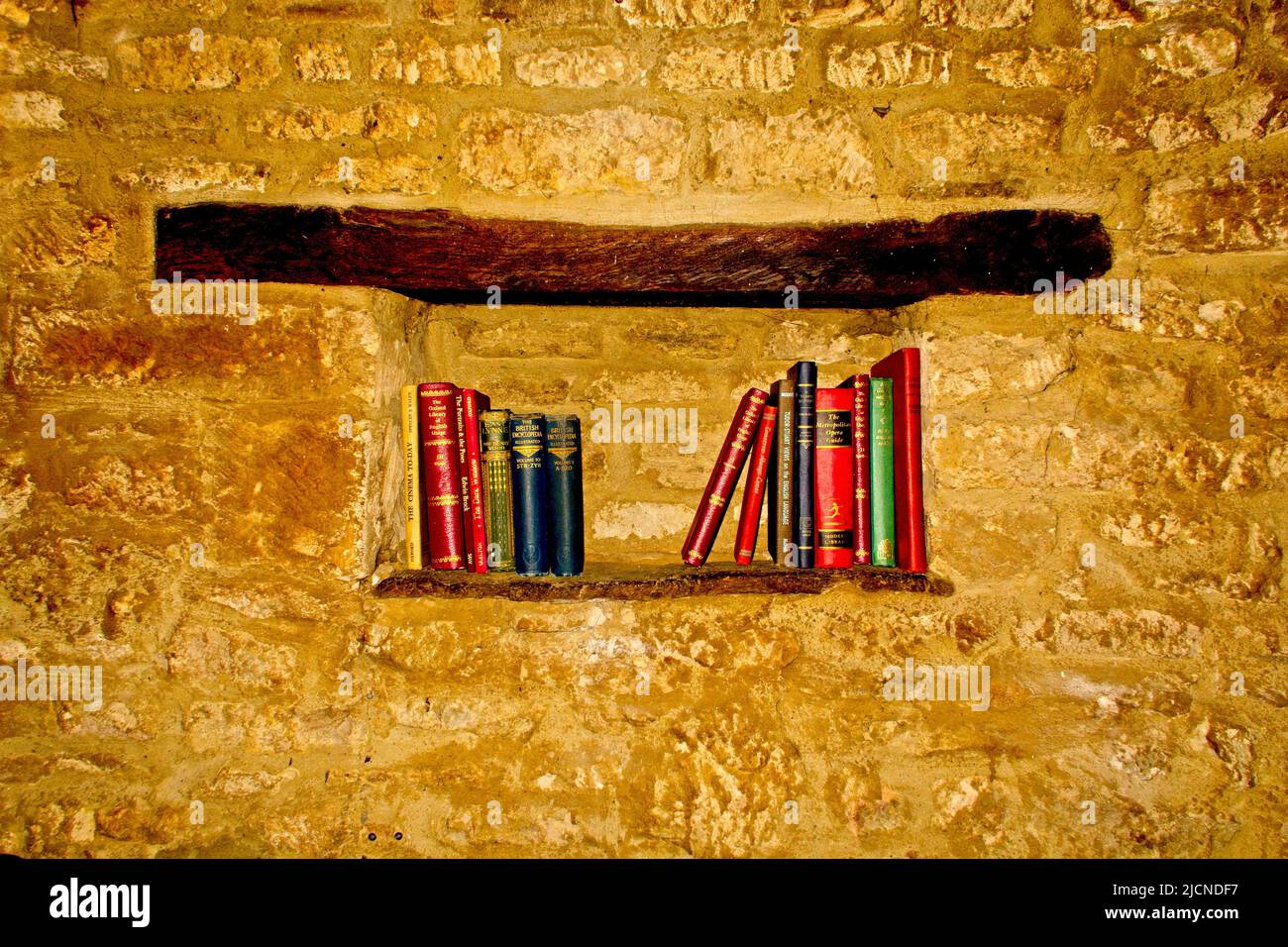 Una mensola posta in un muro di mattone con alcuni libri molto vecchi sopra Foto Stock