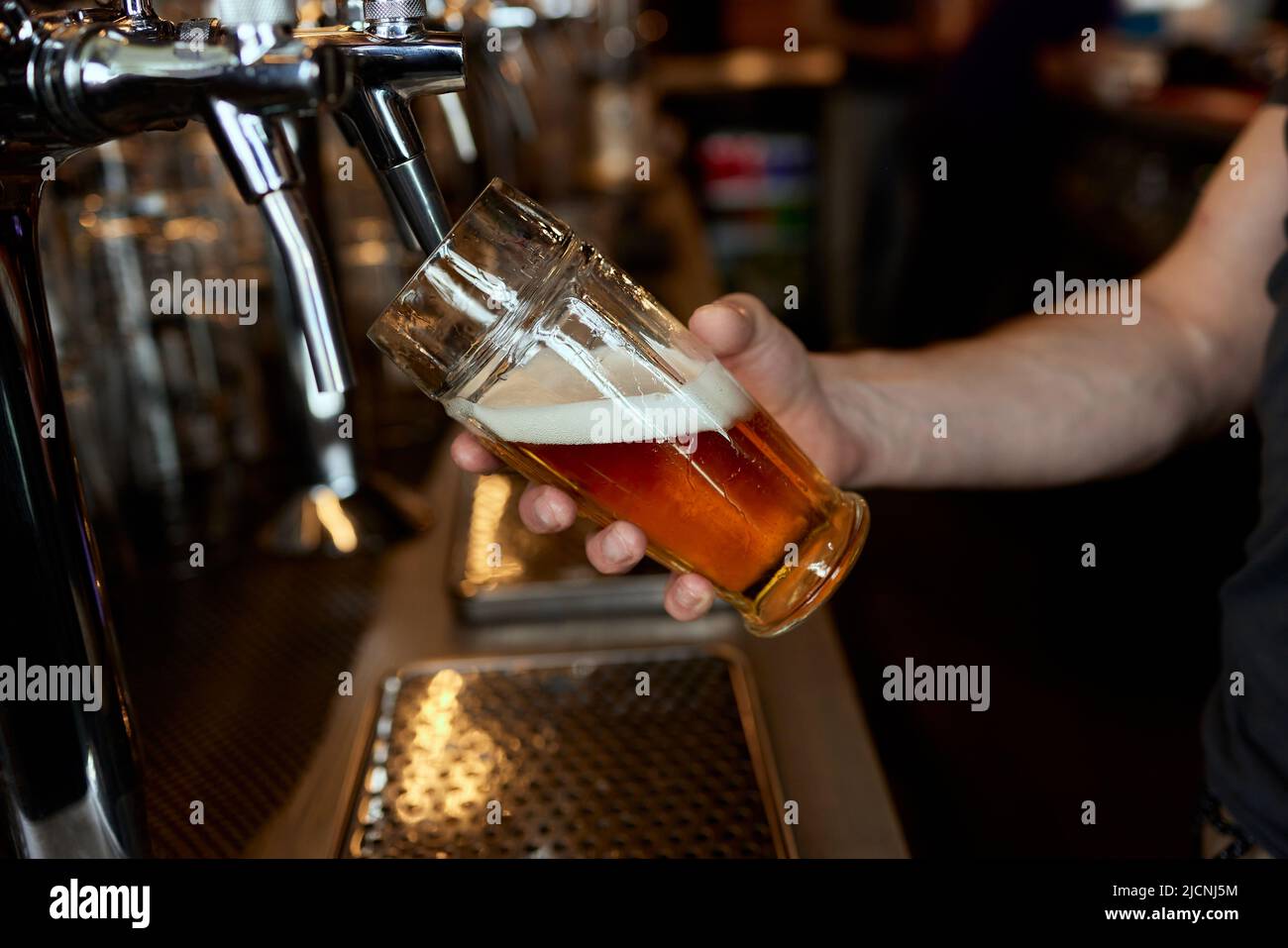 Versare la birra in una tazza in un primo piano della birreria. Imbottigliamento di birra nel ristorante. Il contatore bar Foto Stock