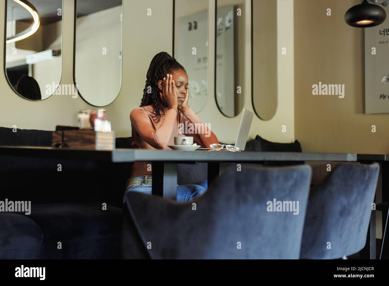 Ansioso e arrabbiato gara mista afro americano donna d'affari, overworking online con notebook in ufficio creativo. Mal di testa Foto Stock