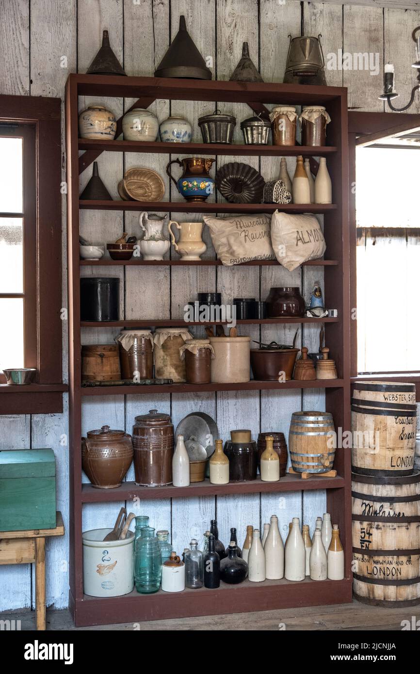 Scaffale che tiene in mano le ceramiche e le bottiglie di cucina nella cucina storica al Fort Nisqually Living Museum di Tacoma, Washington Foto Stock