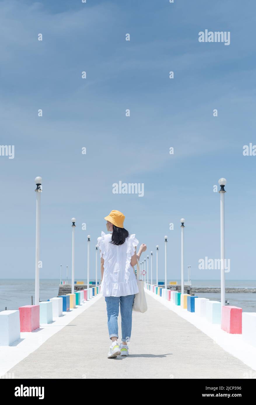 La vista posteriore di una donna asiatica che cammina sul ponte dell'arcobaleno per vedere il punto di vista della provincia di Samut Sakorn, una delle province della Thailandia. Foto Stock