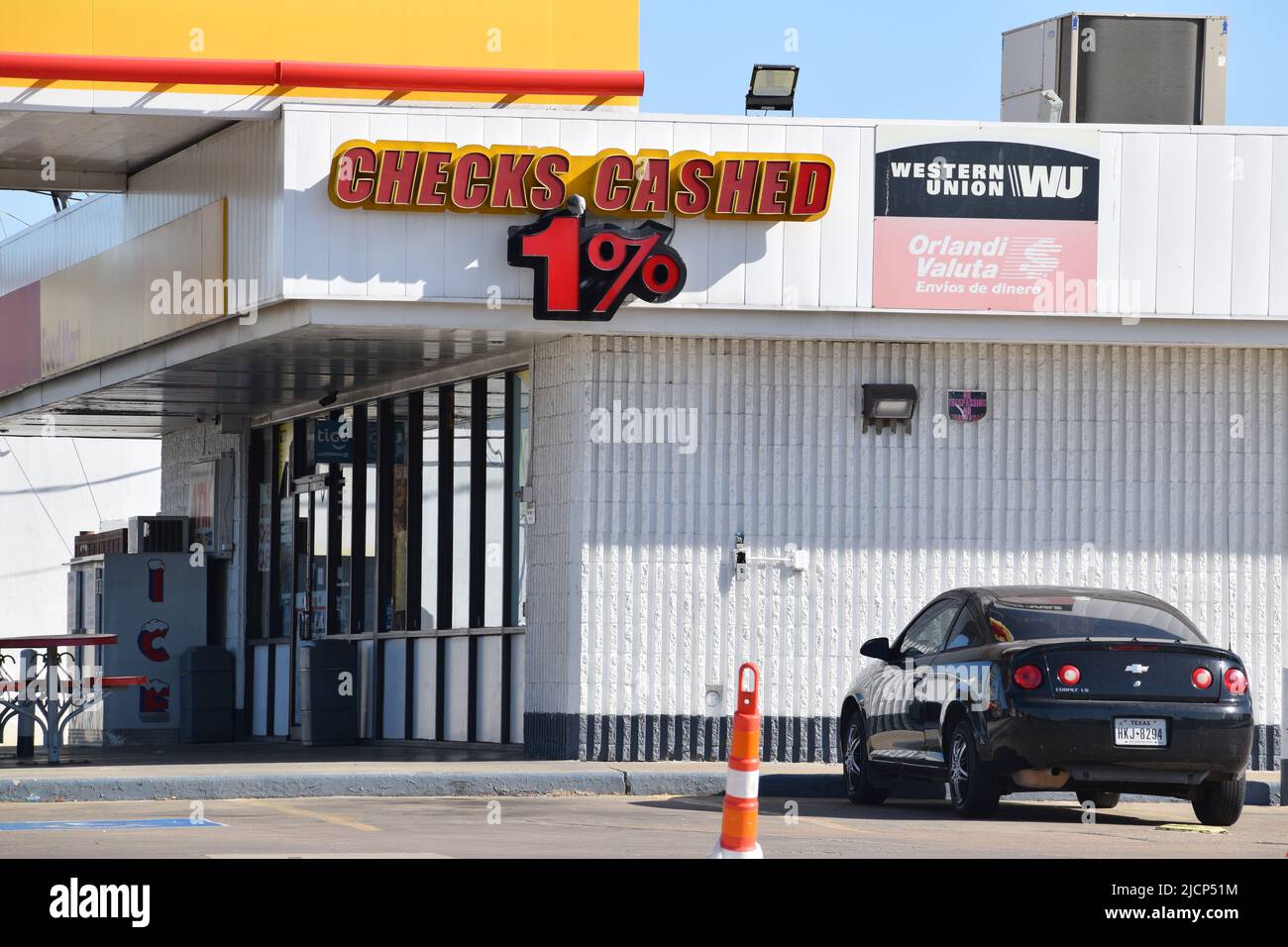 Auto parcheggiata in un minimarket con un cartello "Cheques cased 1%" sulla parete esterna Foto Stock