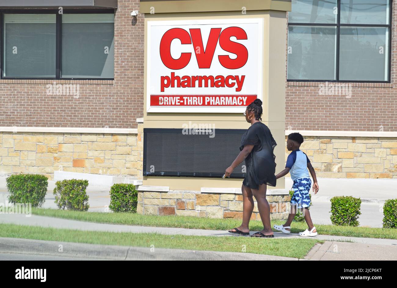 Donna afroamericana che cammina di fronte a un cartello CVS Pharmacy Foto Stock
