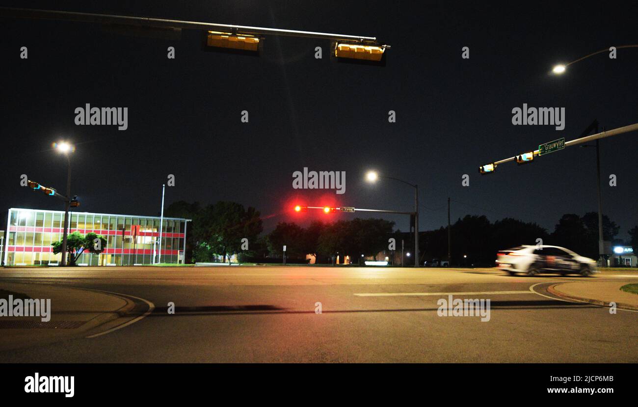 Auto veloce di notte, scendendo lungo una strada dopo i semafori di Irving, Texas Foto Stock