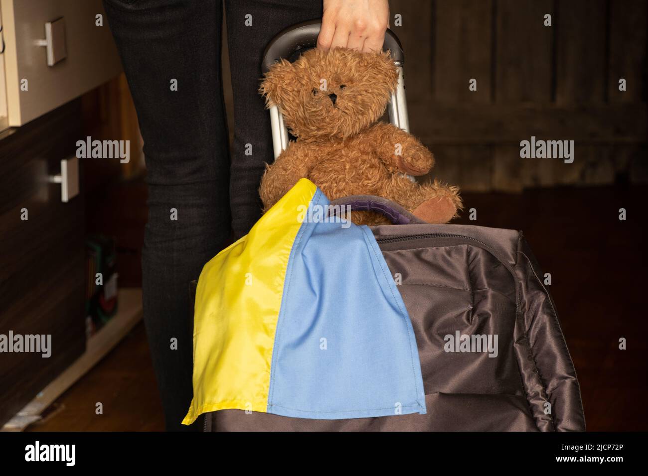 Donna Ucraina con una valigia e un orsacchiotto con la bandiera dell'Ucraina lascia la sua casa a causa della guerra, rifugiati ucraini, lasciare la loro casa 202 Foto Stock
