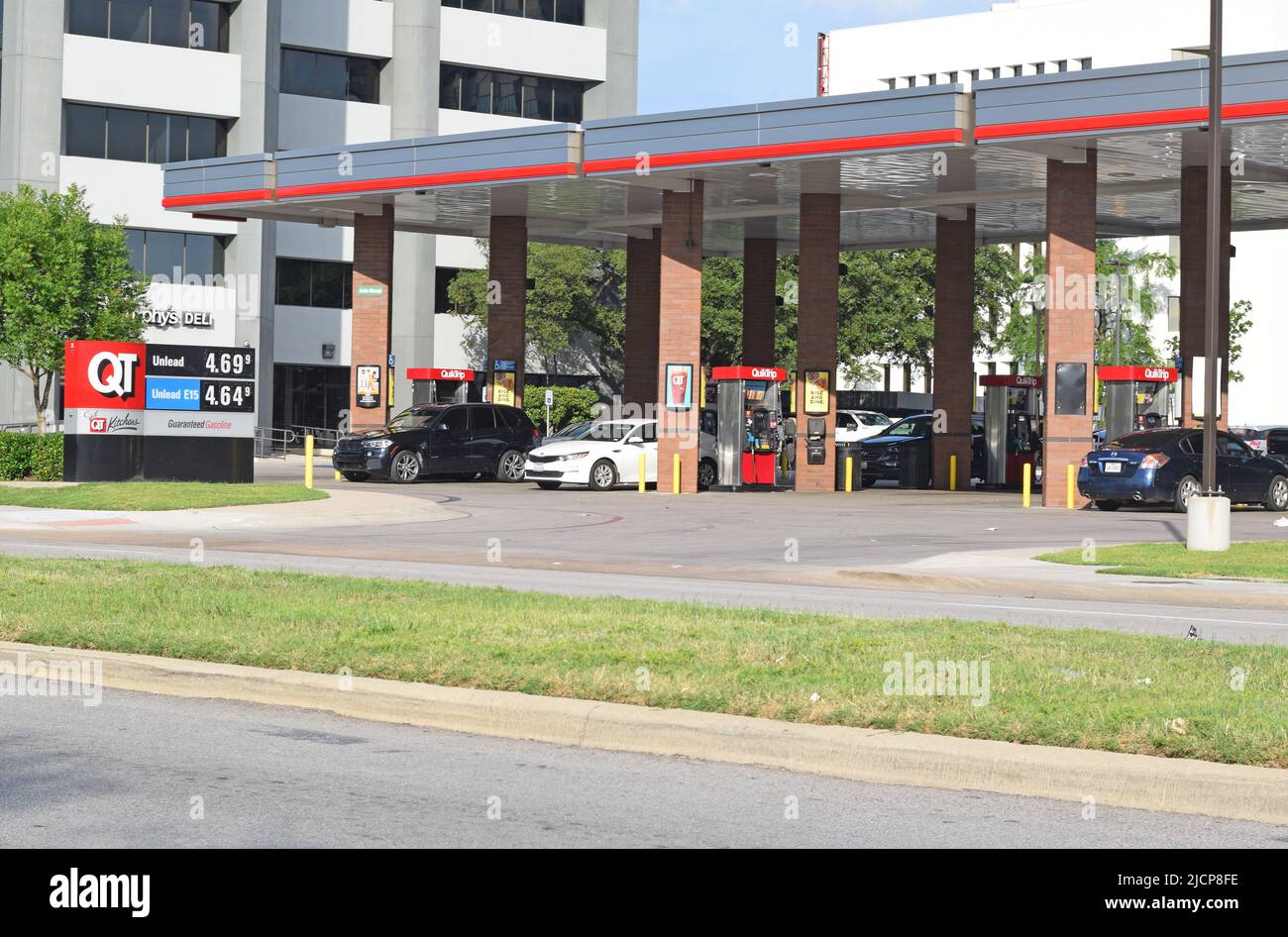 Clienti che pompano benzina in una stazione di servizio Quick Trip; prezzi elevati del gas sul cartello QT Foto Stock