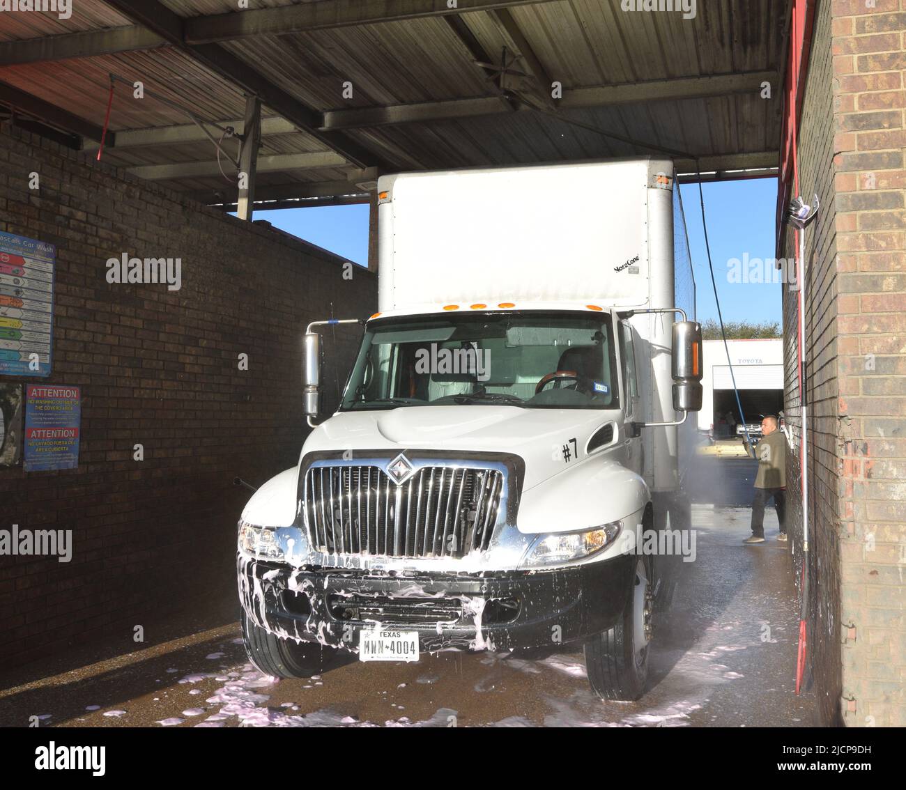 Uomo che lavi un camion di consegna bianco ad un lavaggio del camion a Irving, TX Foto Stock