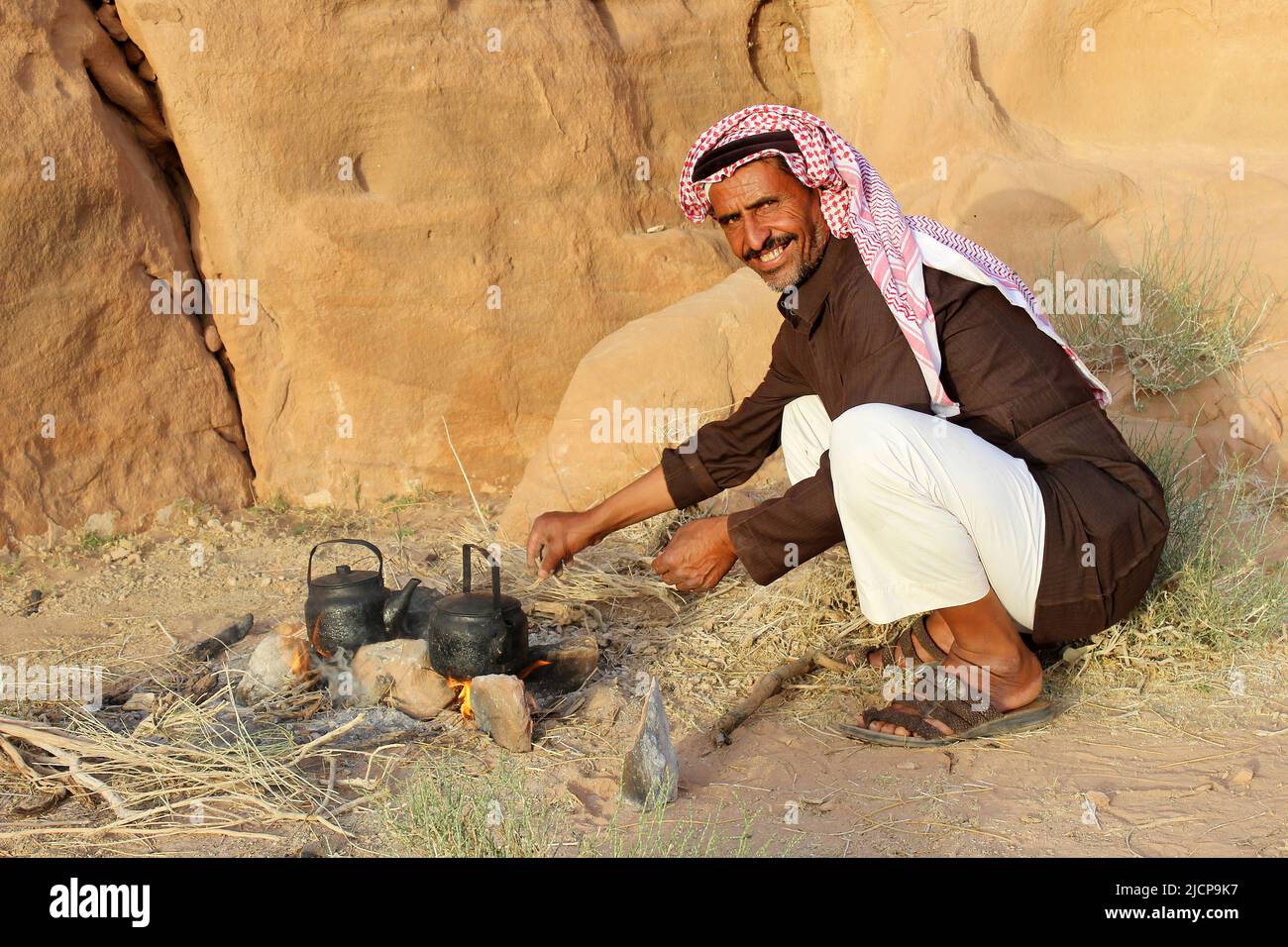 Uomo beduino con bollitore sul fuoco aperto per preparare il tè, Wadi Rum, Giordania Foto Stock