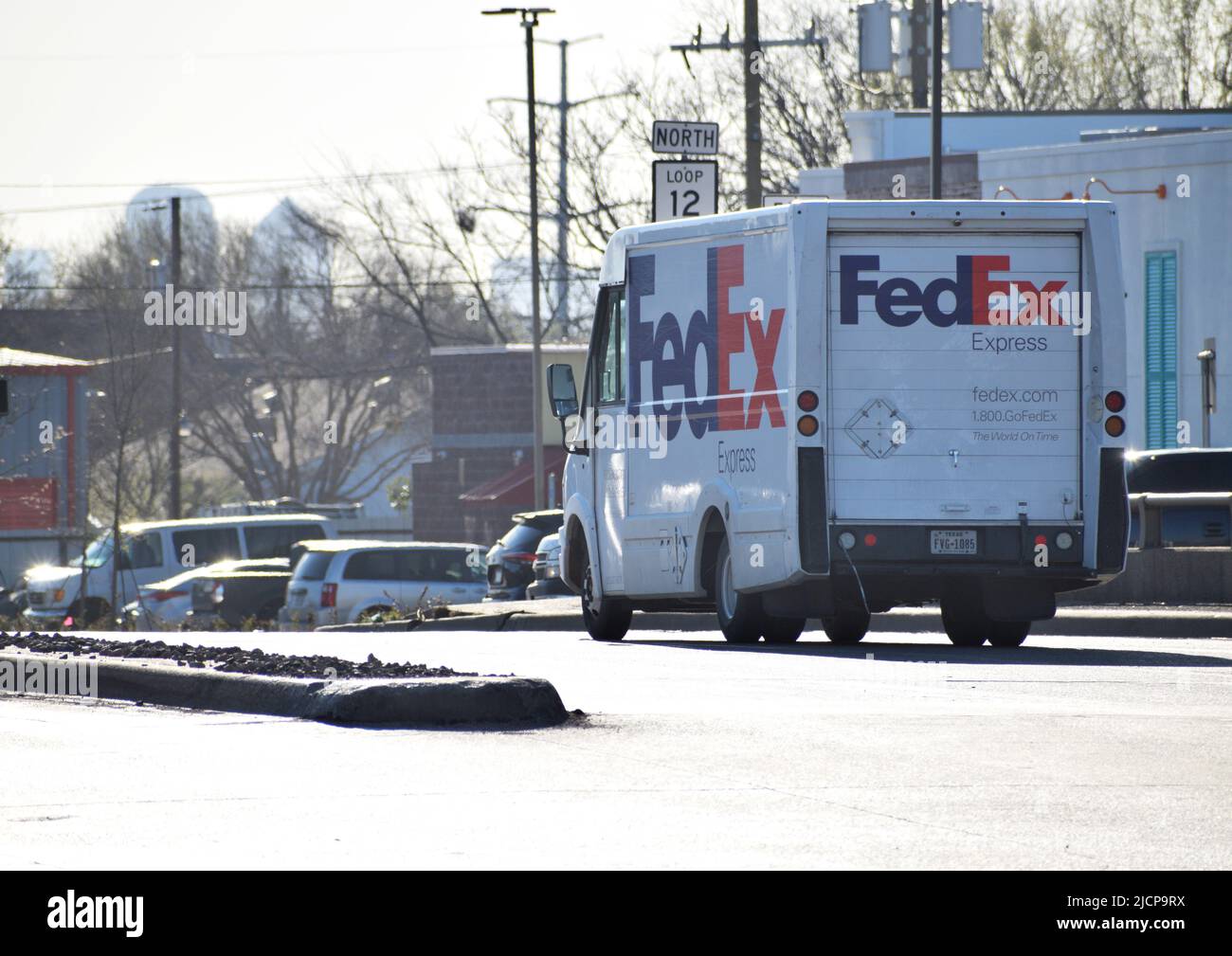 Veicolo di consegna FedEx durante la guida, vista che si allontana dalla telecamera, rivolta verso sinistra Foto Stock