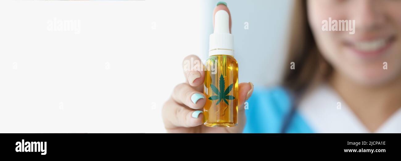 L'operatore medico presenta l'olio di cannabis in bottiglia di plastica per un trattamento alternativo Foto Stock