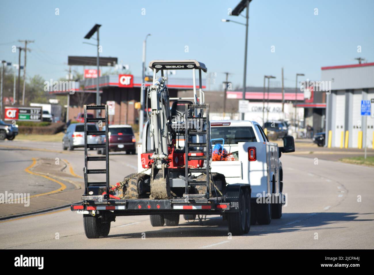 Un autocarro da lavoro che traina un escavatore compatto Takeuchi su un rimorchio Foto Stock