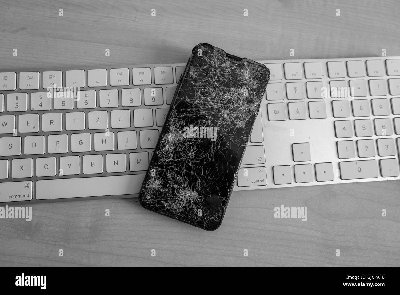 un telefono cellulare completamente distrutto giace su una tastiera del computer Foto Stock