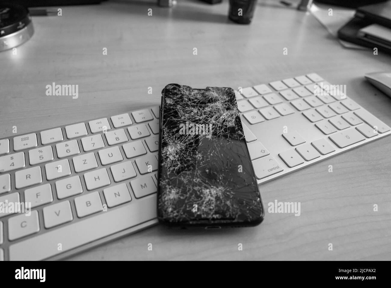 un telefono cellulare completamente distrutto giace su una tastiera del computer Foto Stock