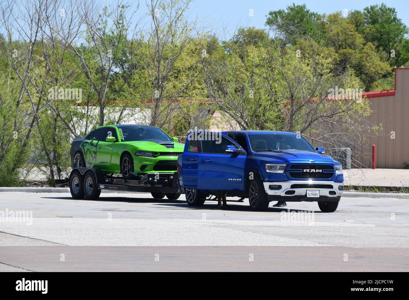 Un camion blu Dodge RAM Pick up che tira una vettura sportiva verde su un rimorchio Foto Stock