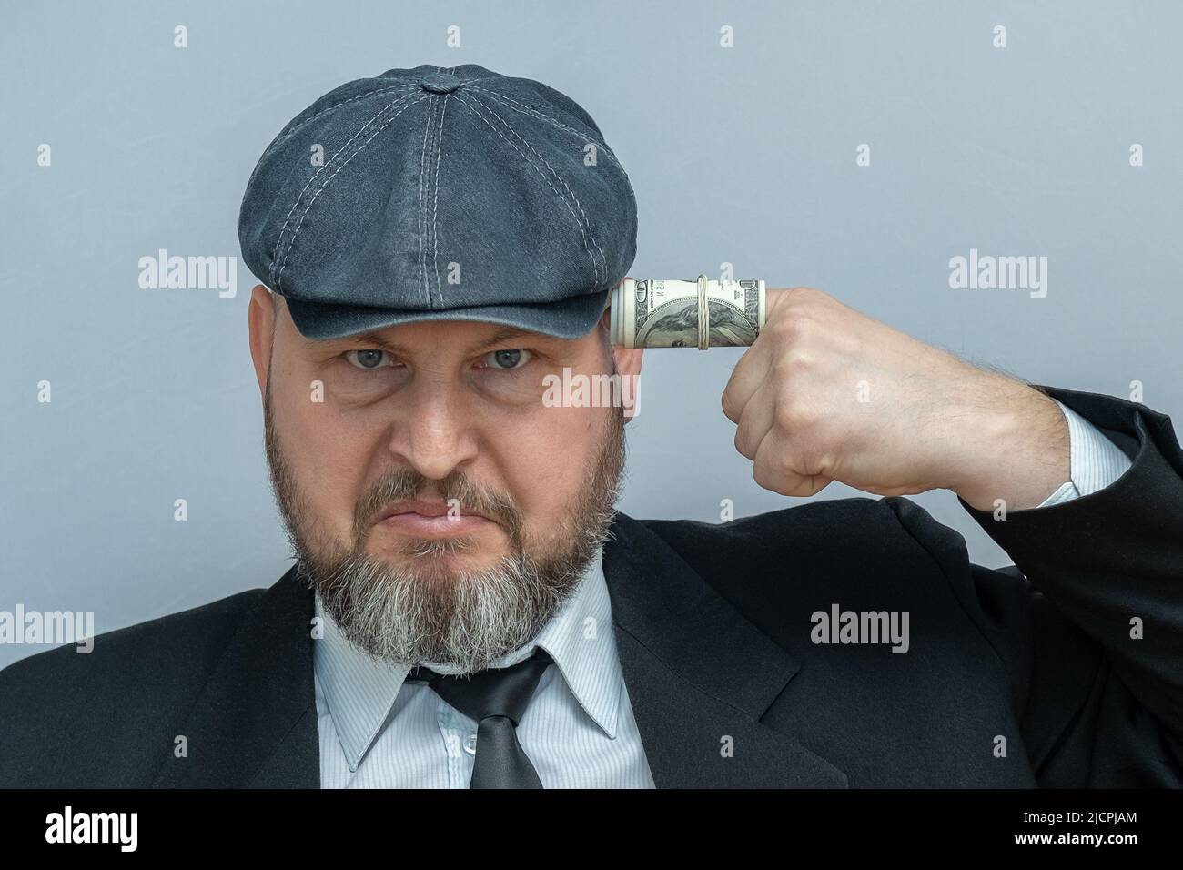 L'uomo mise il dito sul suo tempio. Il dito è avvolto in una fattura del dollaro. Sembra che voglia sparare a se stesso. Foto Stock