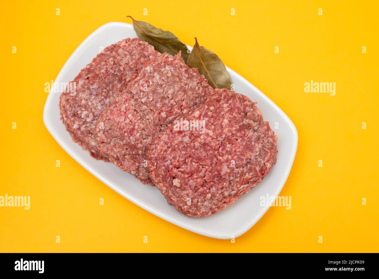 carni fresche macinate crude su piatto bianco con alloro Foto Stock