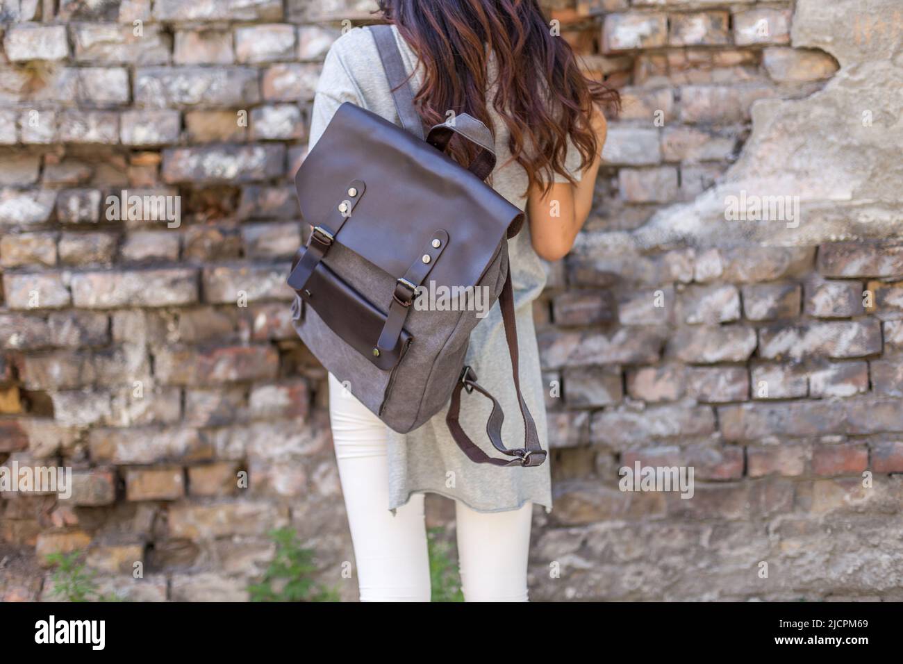 Schiena di donna con zaino in tela grigia. Borsa UNISEX in vendita. Foto Stock