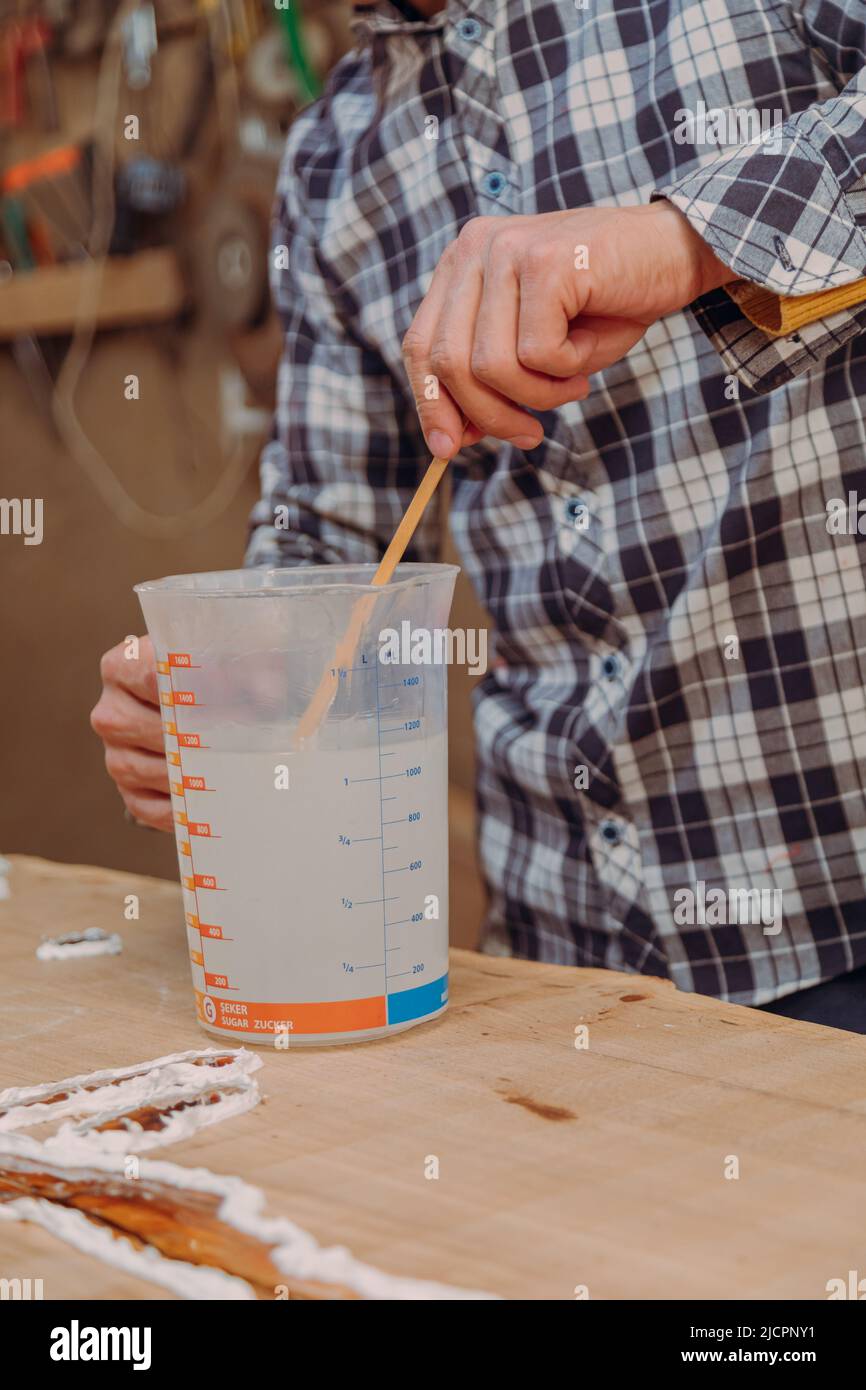 Carpentiere preparazione resina epossidica. Processo di fabbricazione di una resina artigianale e tavola di legno Foto Stock