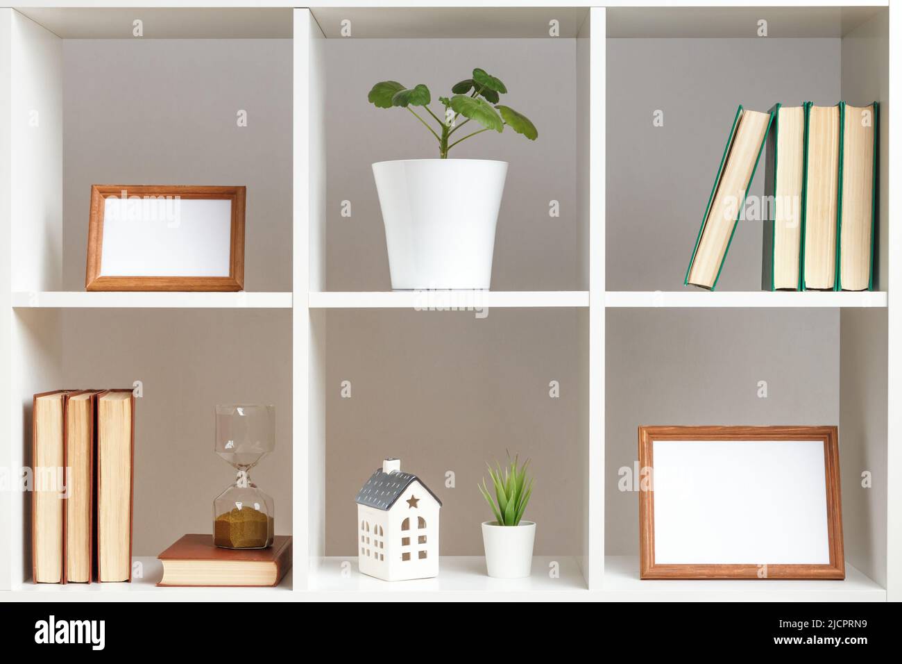 Ripiani bianchi con piante in vaso, cornici fotografiche, libri. Interni per la casa, elementi decorativi. Foto Stock