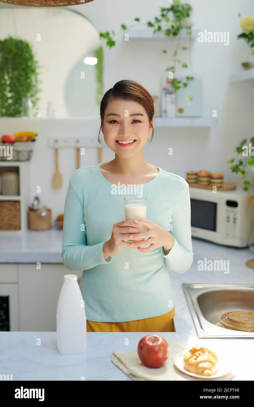 Sorridente donna attraente avente la colazione nella cucina interno Foto Stock