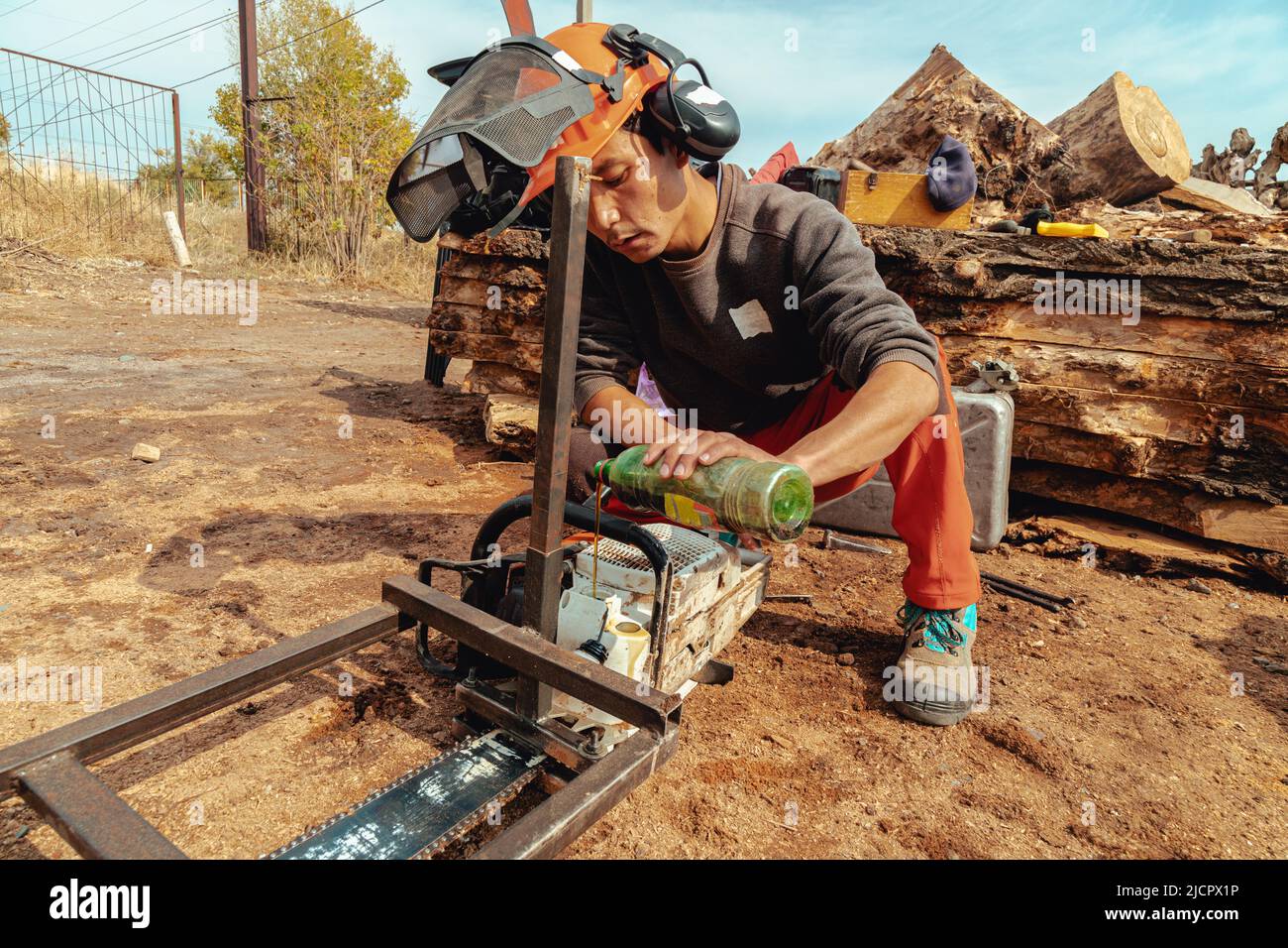Lumberjack versare l'olio nel serbatoio dell'olio per motosega Foto Stock