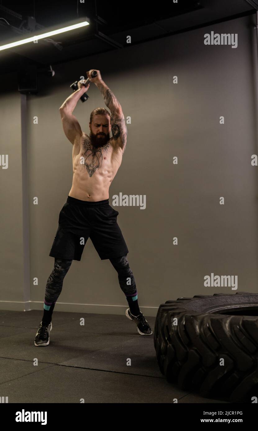 Pneumatico muscle martello barba ruota tatuaggio slitta uomo fitness corpo, concetto atleta allenamento da pesante da club caucasico, muscolo maschile. Attività enorme Foto Stock