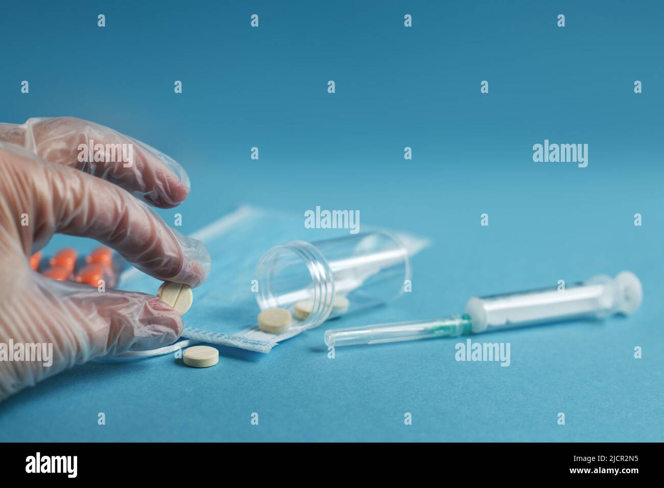 maschera medica, siringa e compresse si chiudono su sfondo blu. Coronavirus, influenza, malattie respiratorie concetto. Orientamento orizzontale. Vista dall'alto. Foto Stock