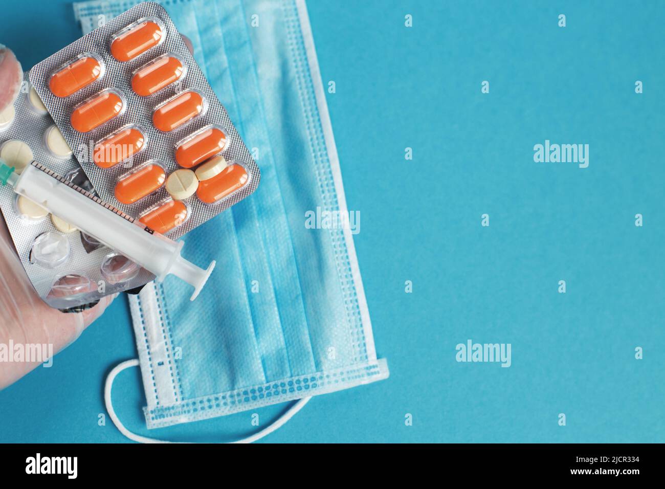 maschera medica, siringa e compresse si chiudono su sfondo blu. Coronavirus, influenza, malattie respiratorie concetto. Orientamento orizzontale. Vista dall'alto. Foto Stock