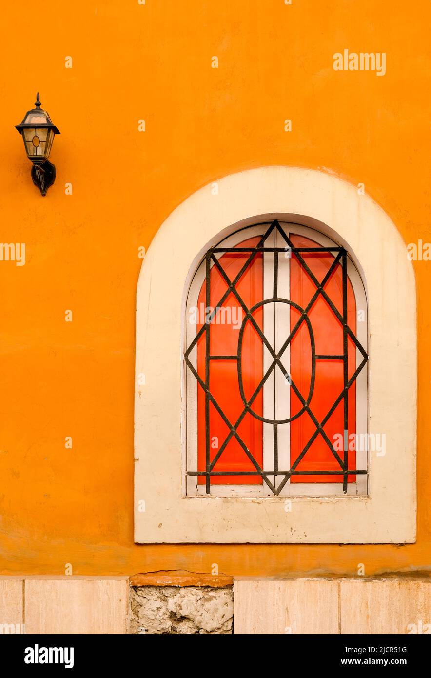 Finestra ad arco con grata di ferro posta in intonaco arancione a Roma. Foto Stock