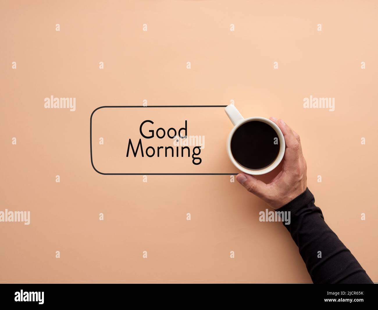 Una mano tiene una tazza di caffè con la parola Buongiorno. Colazione e caffè del mattino. Foto Stock