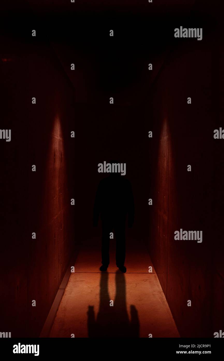 figura misteriosa in piedi in un corridoio stretto e scuro Foto Stock