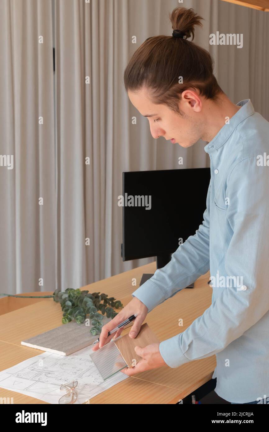 Professionista del design degli interni che mostra e tocca campioni di materiale al cliente su un tavolo in ufficio Foto Stock