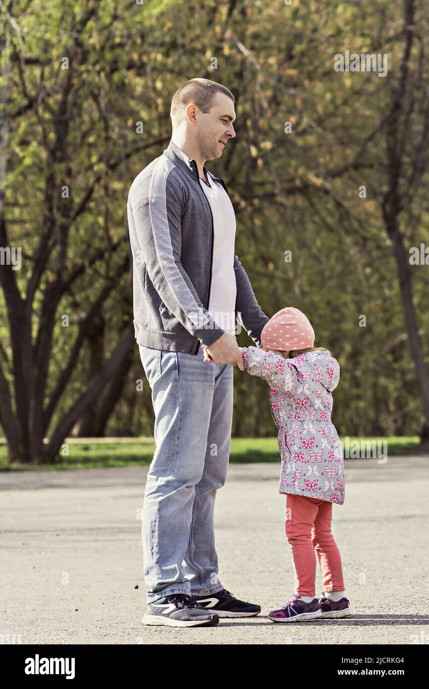 Papà gioca con le sue figlie nel parco. Girando una ragazza intorno. Famiglia. Foto Stock