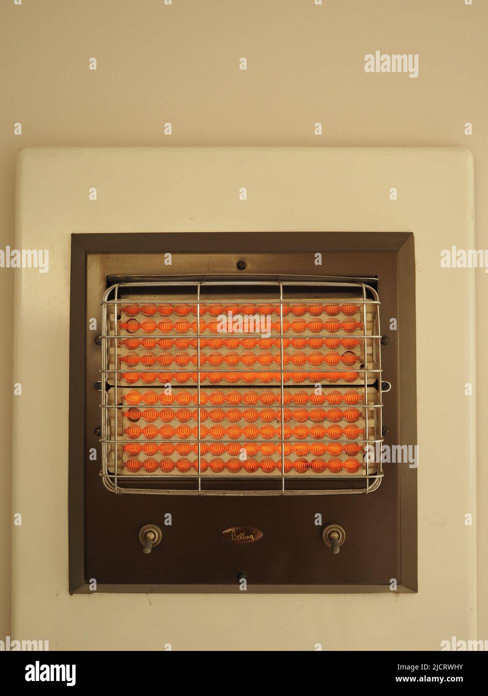 Il riscaldatore elettrico Belling 1950s o 1960s, montato a parete, a doppio controllo, è mostrato in funzione e in arancione brillante. Foto Stock