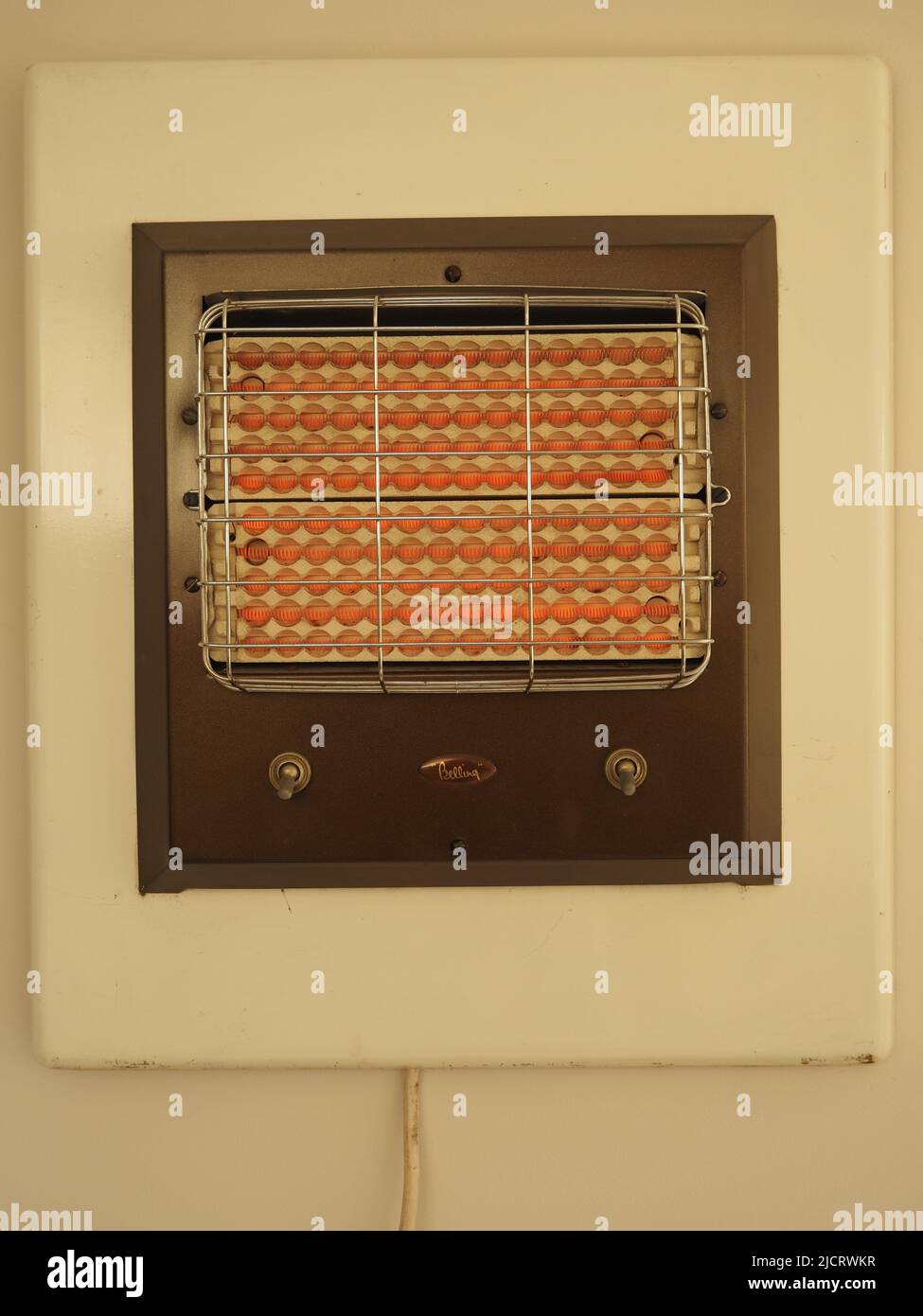 Il riscaldatore elettrico Belling 1950s o 1960s, montato a parete, a doppio controllo, è mostrato in funzione e in arancione brillante. Foto Stock