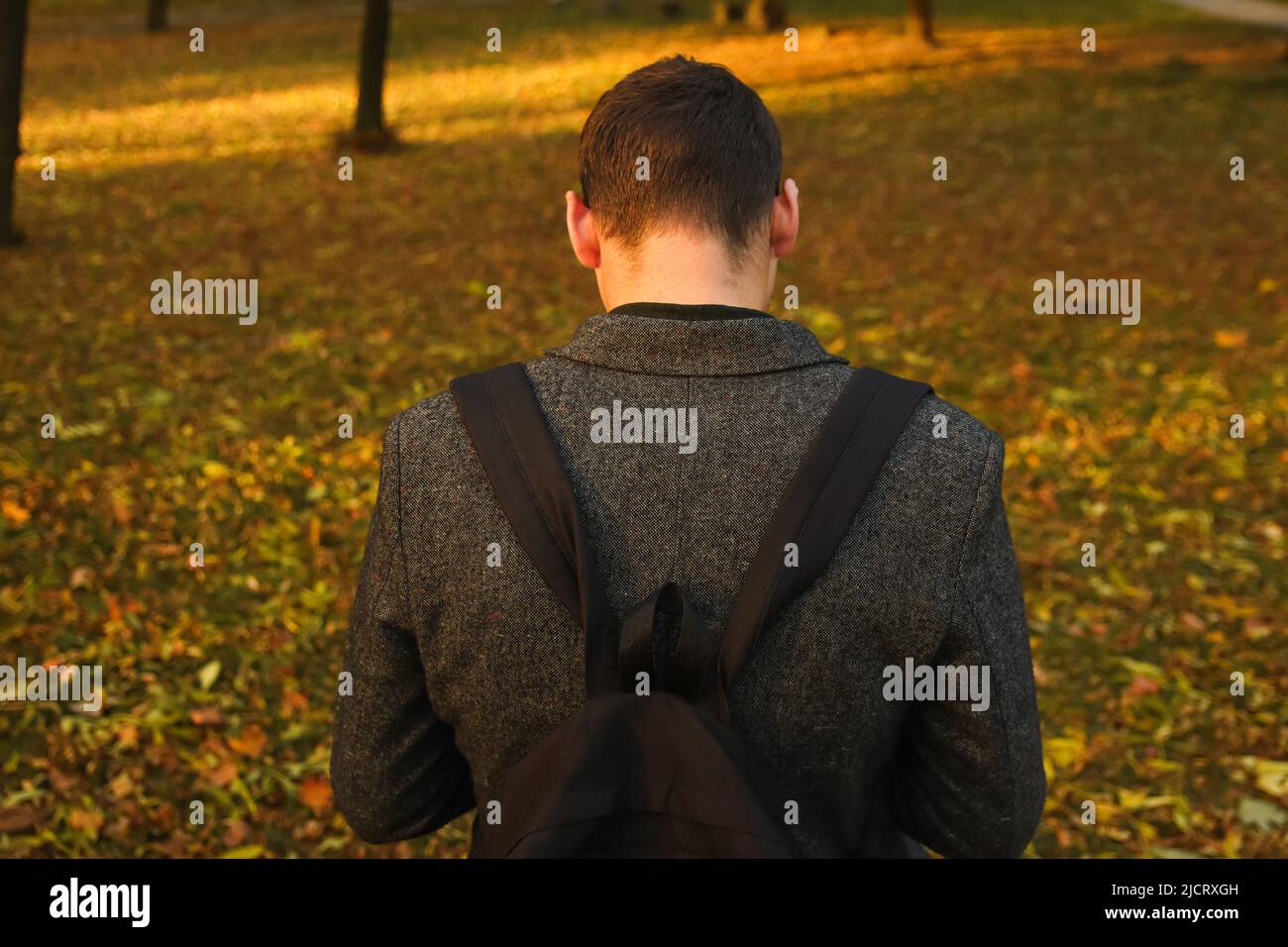 Defocalizzare il giovane uomo che tiene il telefono. Uomo che usa lo smartphone nel parco autunnale. Digitare un messaggio di testo o leggere i social media sul telefono cellulare. Sfondo autunno Foto Stock