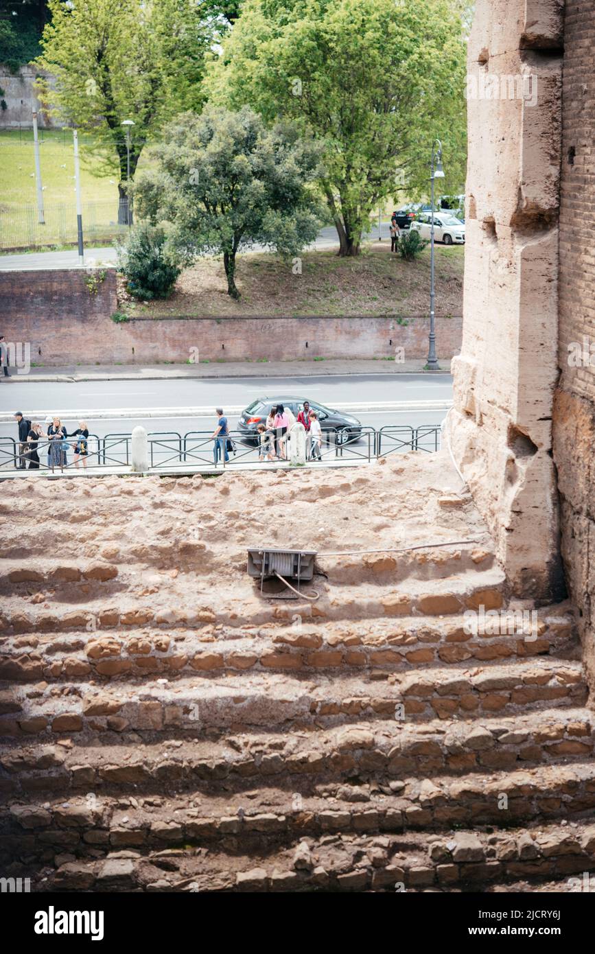 Vista panoramica sulla strada trafficata con alberi verdi e antiche rovine nel centro storico di Roma Foto Stock