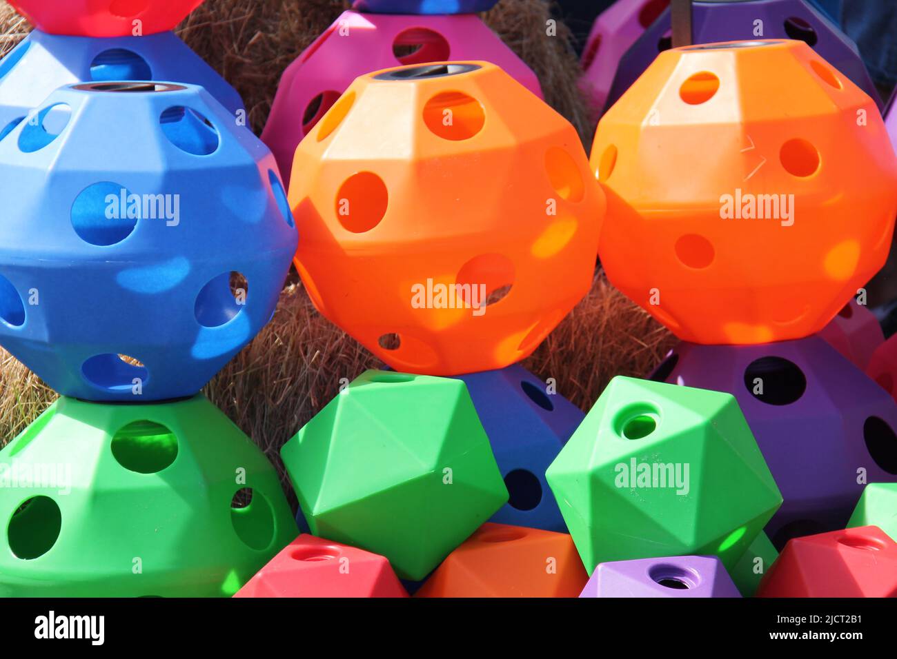 Vari colori e dimensioni di sfere di plastica di alimentazione animale di fieno. Foto Stock