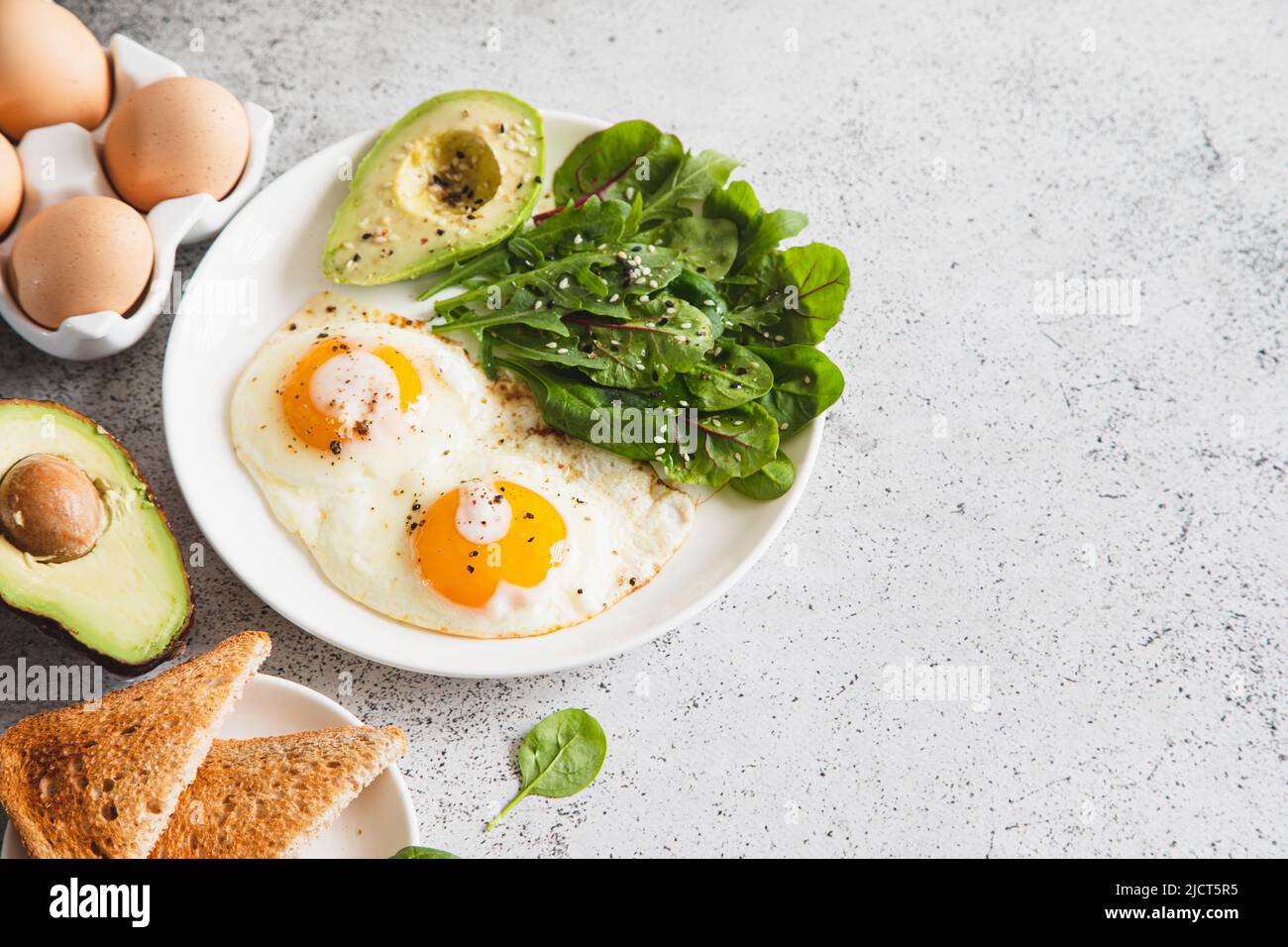 Colazione salutare con pane tostato integrale, uova con insalata verde, avocado. Colazione tradizionale Foto Stock