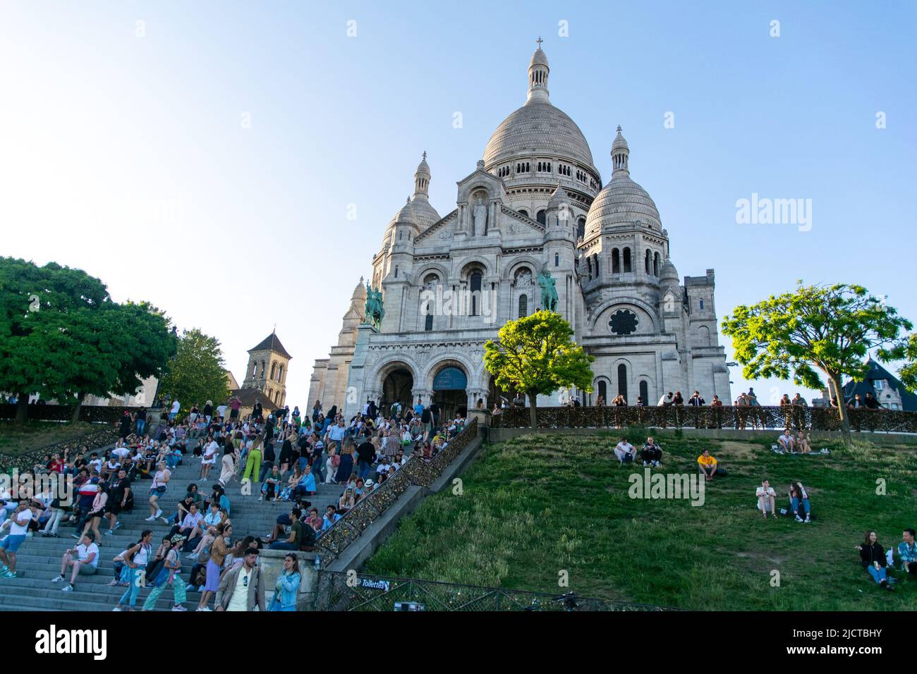 I turisti si siedono alle scale sotto la chiesa del Sacro cuore, Montmartre, Parigi Foto Stock